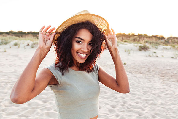 Young woman earing a sun hat and smiling on the beach