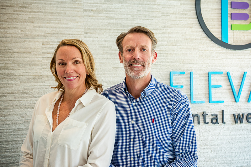 Drs. Rebecca Steinbach and Schuyler Van Gorden in front of Elevate Dental Wellness logo