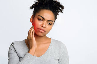 Woman touching jaw with visible redness, showing discomfort from TMJ disorder or dental pain.